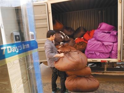 3月20日，7天连锁酒店（北京鸟巢体育场店）门口，丰台区大灰厂村的洗涤厂工人将待洗的布草搬运上车。